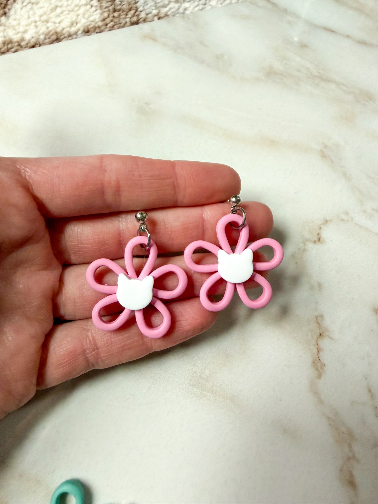 Pink flower dangles with a white cat head in the center. 