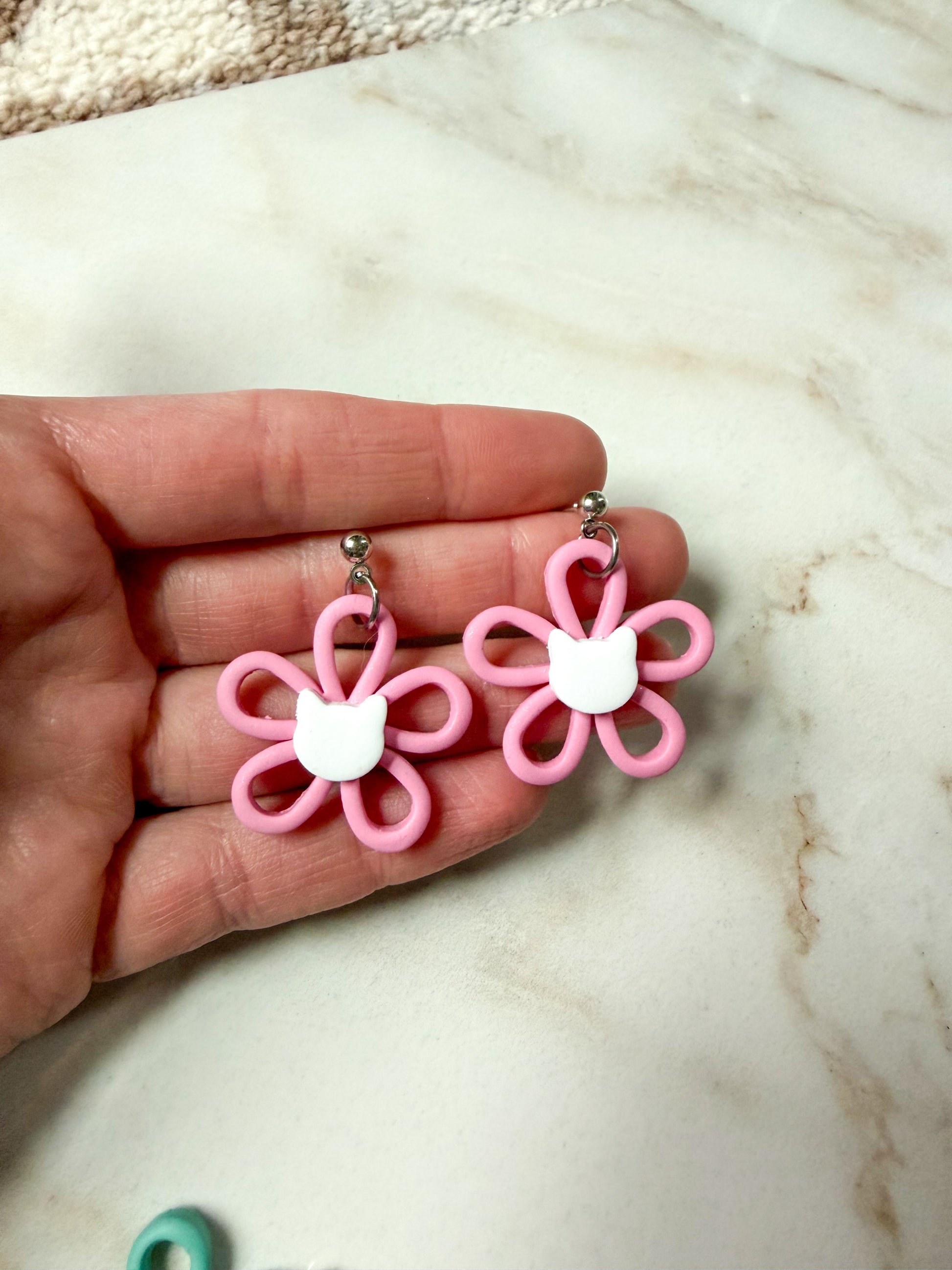 Pink flower dangles with a white cat head in the center. 
