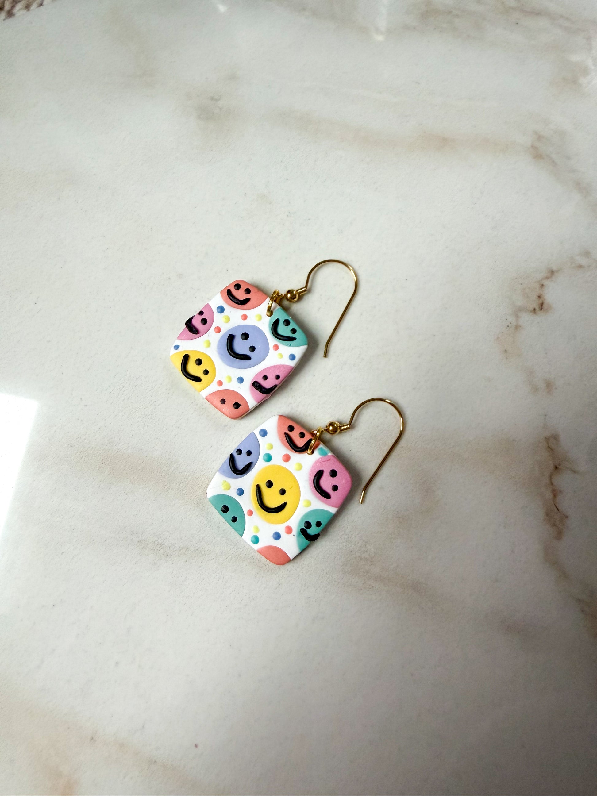 Colorful smiley face earrings on a marble surface