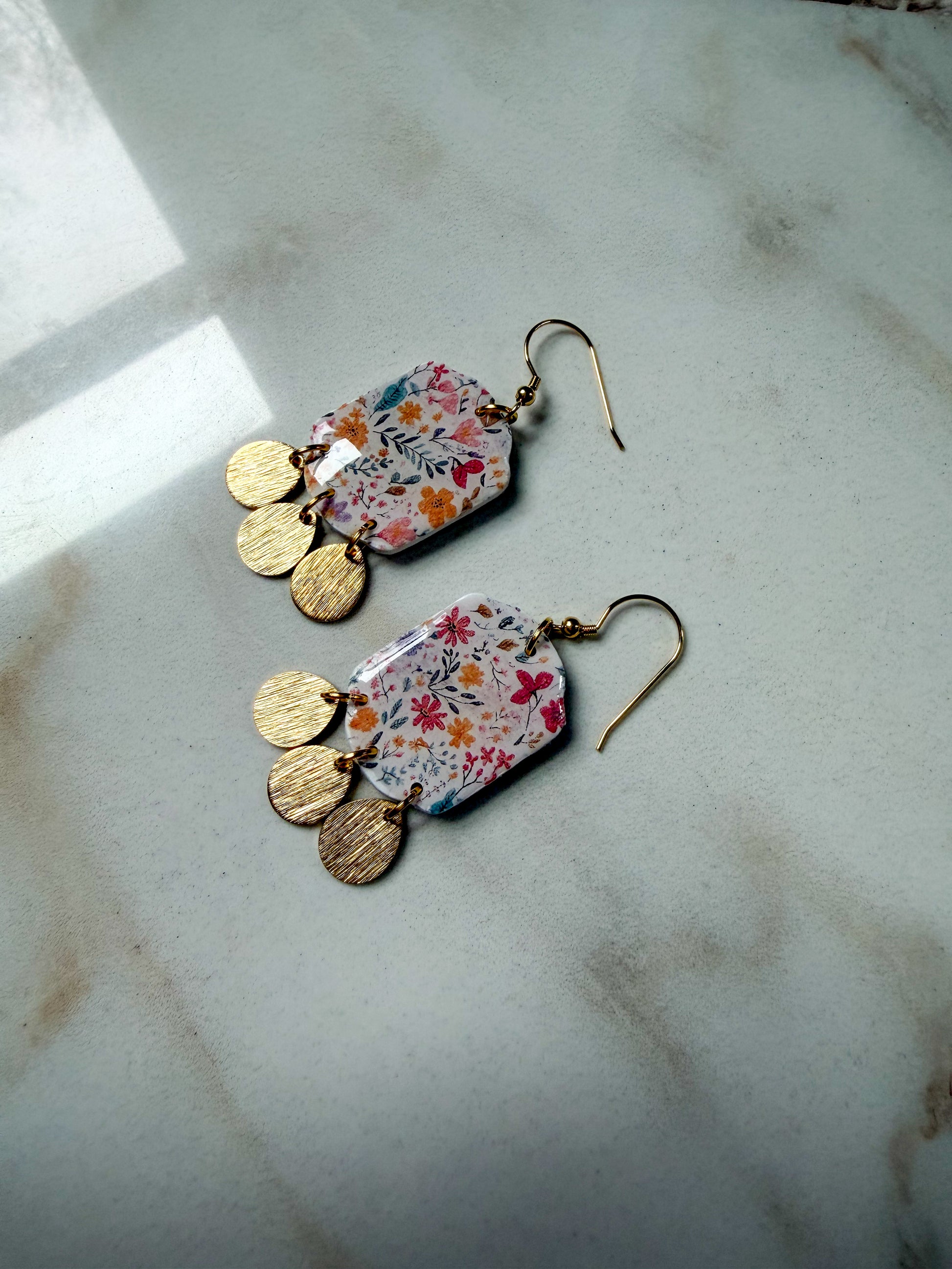 Pair of floral earrings with gold accents on a marble surface