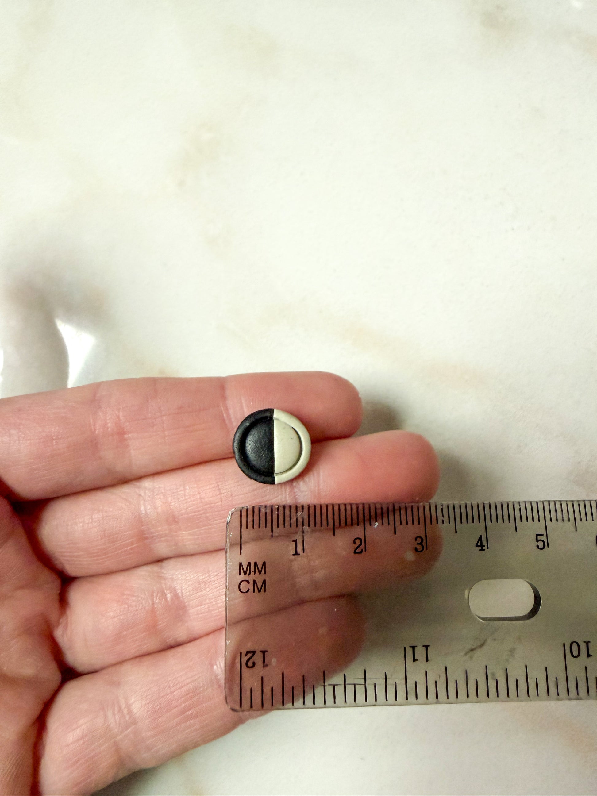 Framed circle studs in front of a ruler for scale. About 1 cm in length