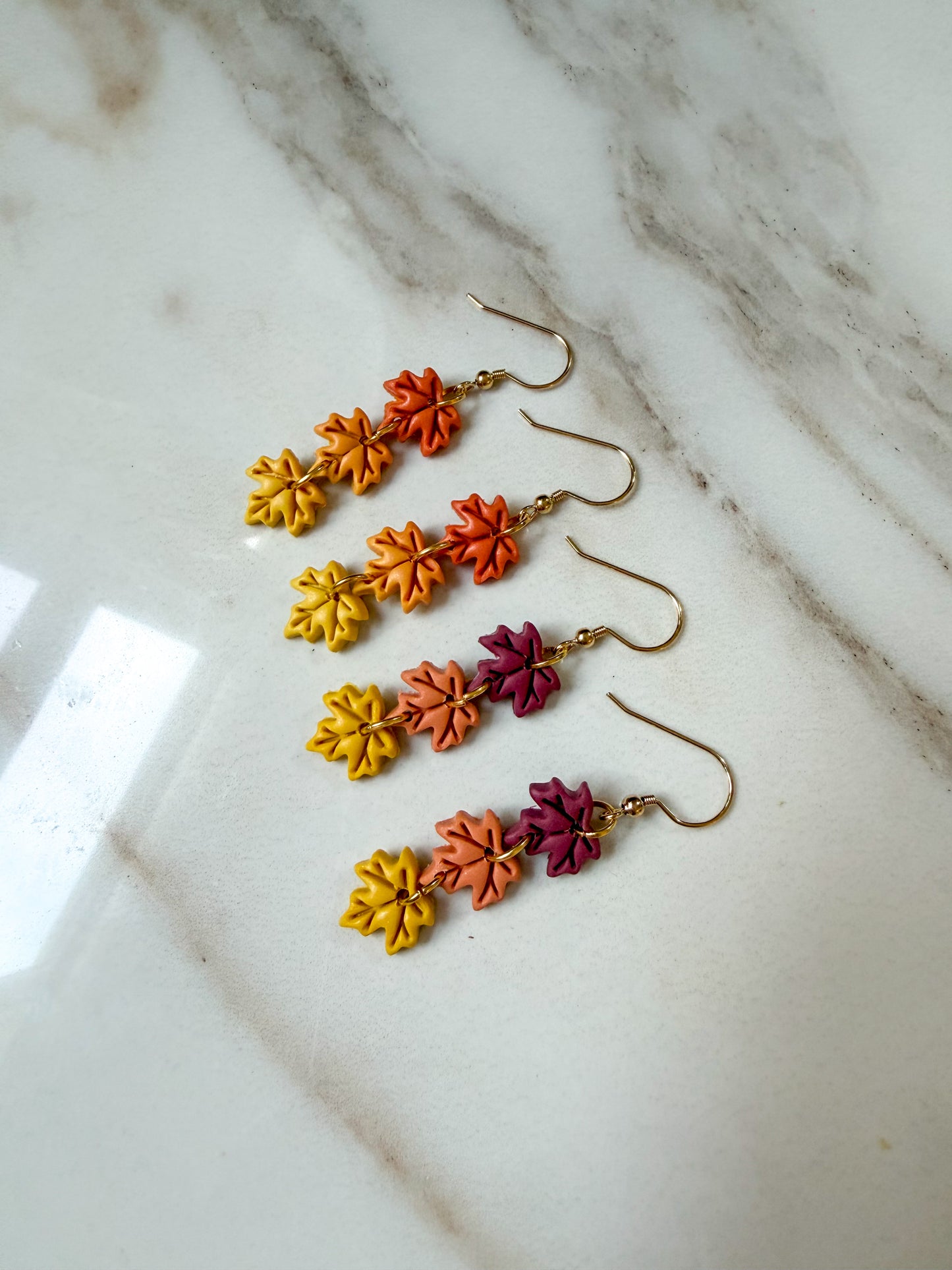 Two pairs of leaf dangles on a marble surface. 