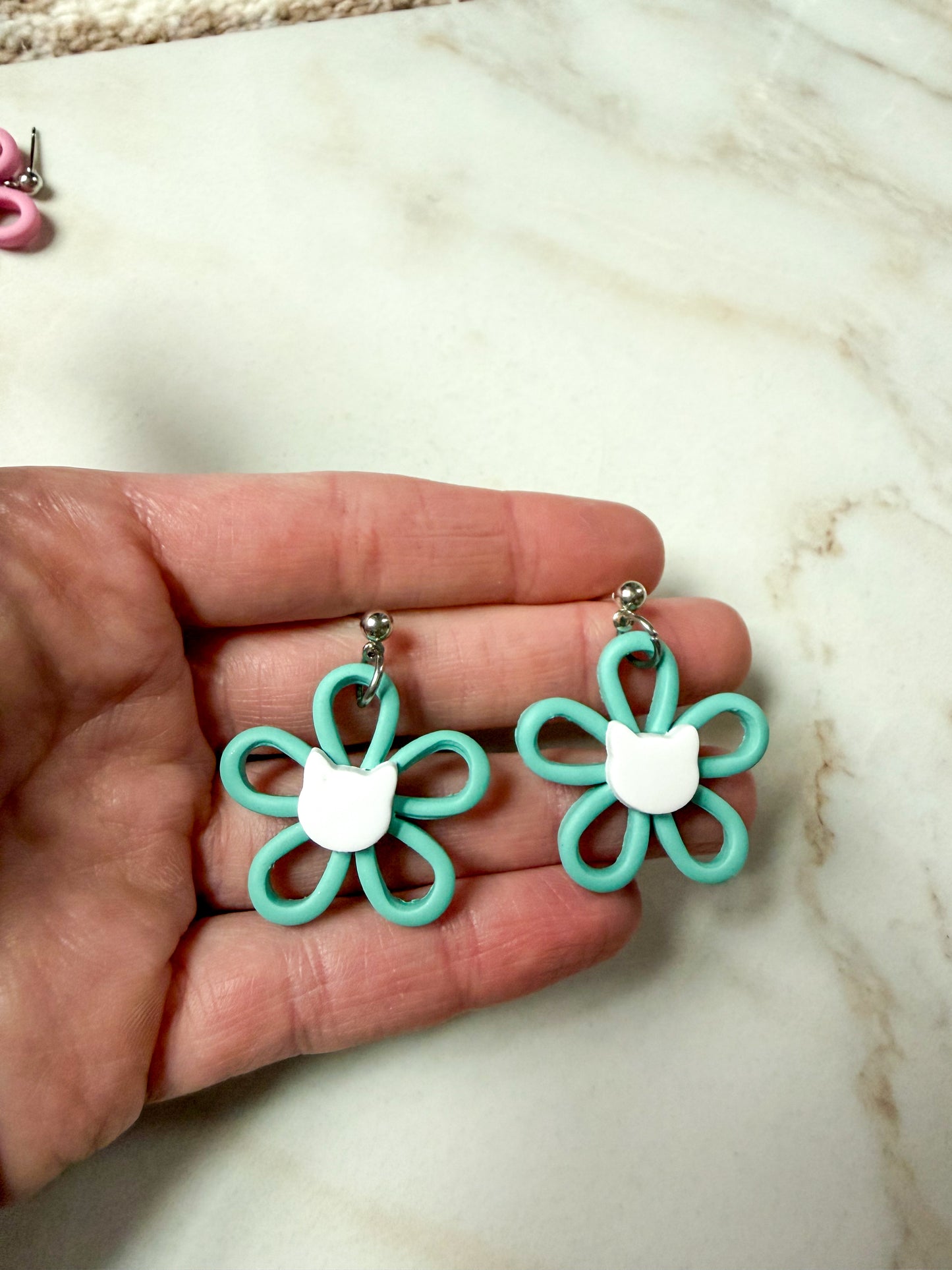 Green flower dangles with a white cat head in the center. 