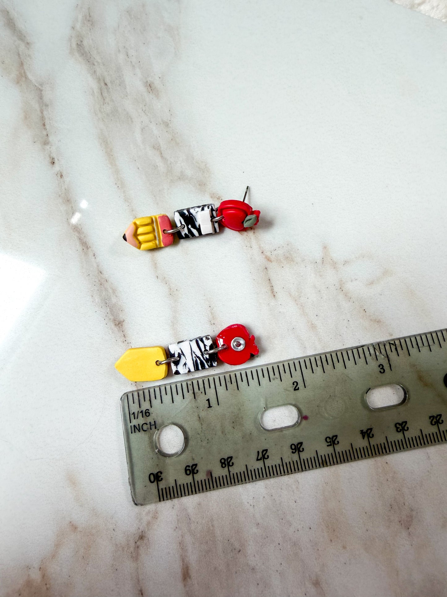 Earring next to a ruler for scale. About 1 1/2 inches in length. 
