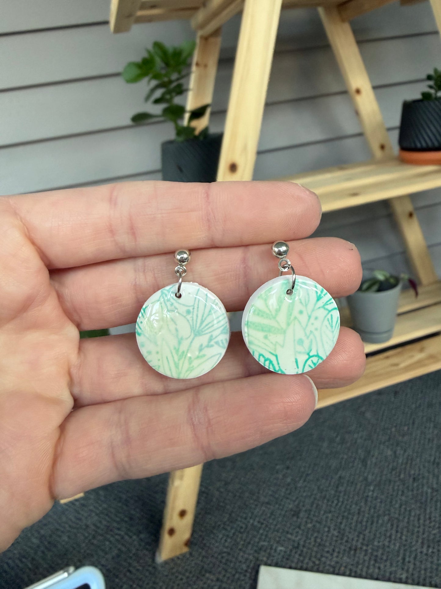 Green and white floral dangles in a hand.