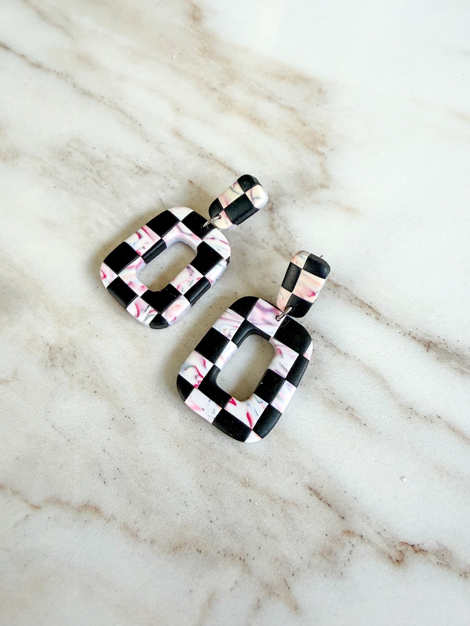 Pair of checkered earrings on a marble surface