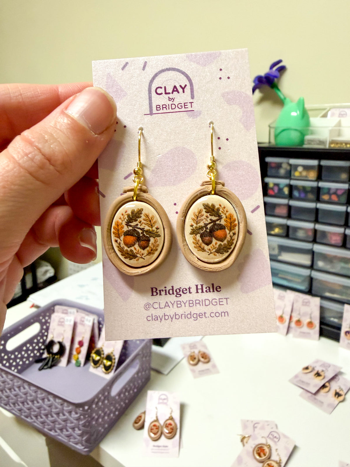 Embroidery hoop shaped earrings with an acorn design in the center. 