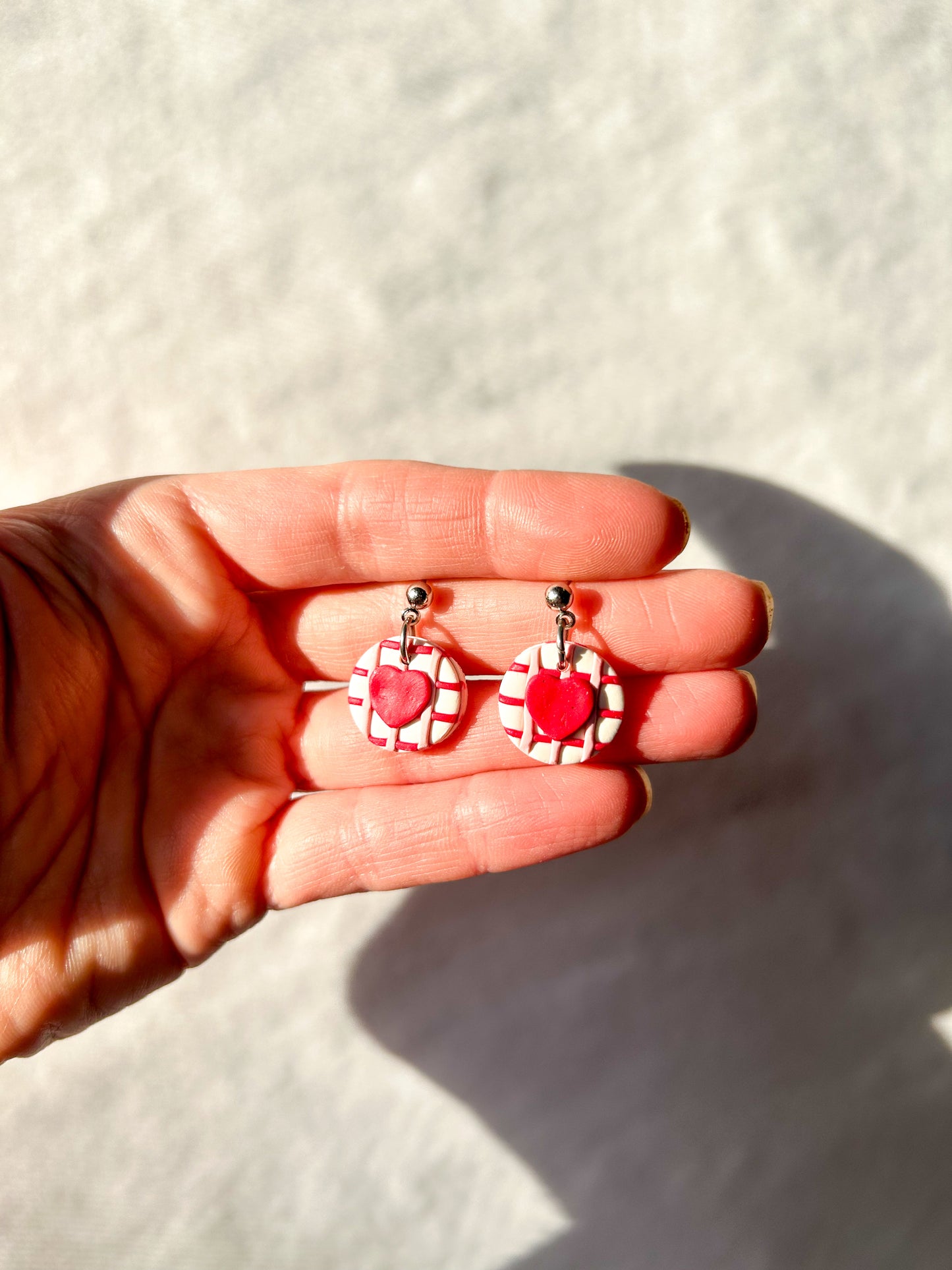 Handholding a pair of circle dangles with hearts in the center