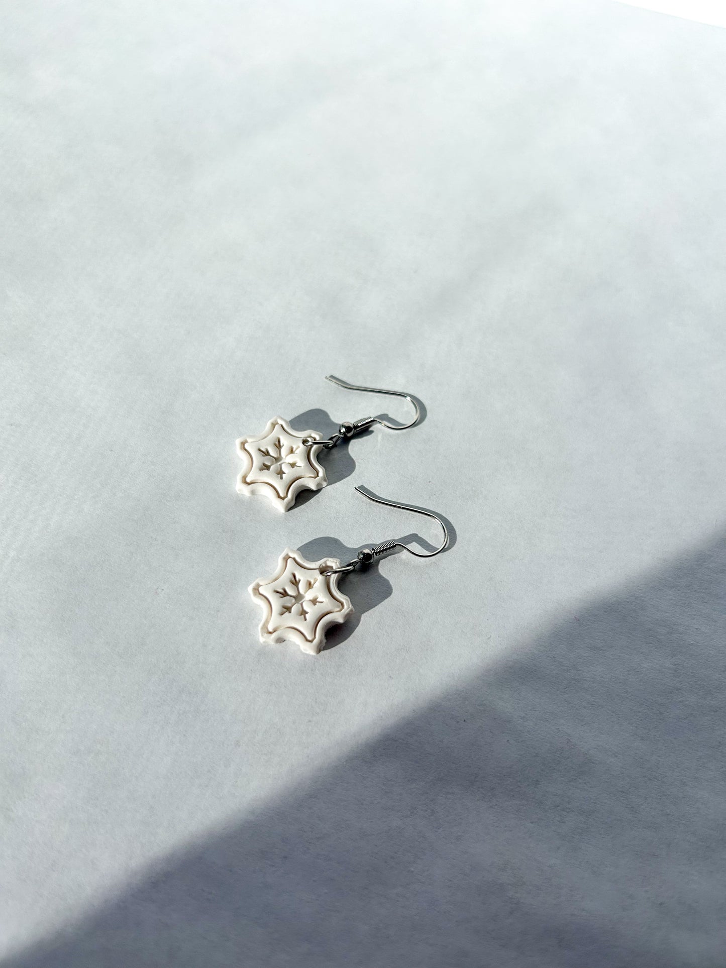 White snowflake earrings on a light gray background