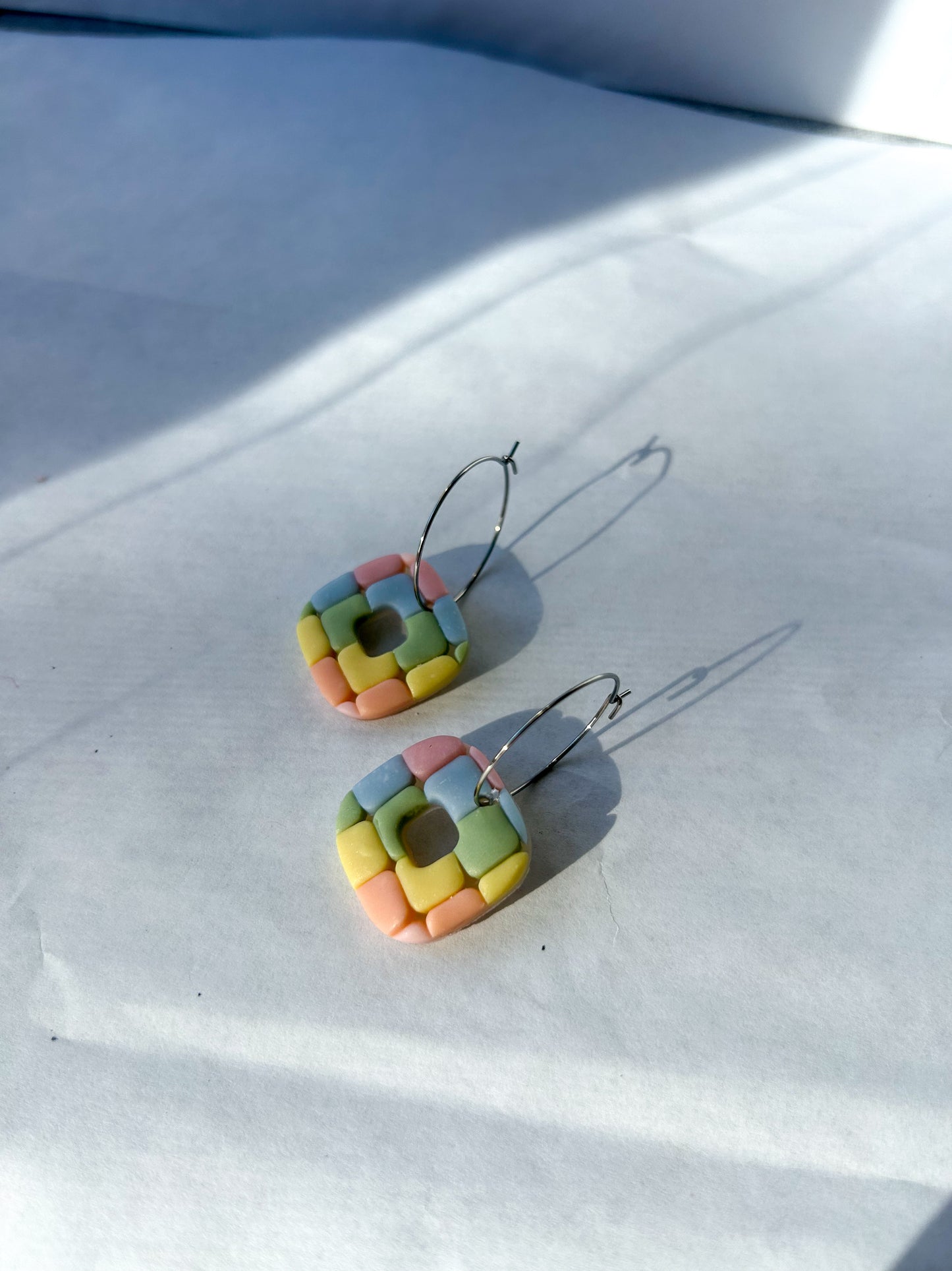 Colorful square-shaped earrings on a white surface