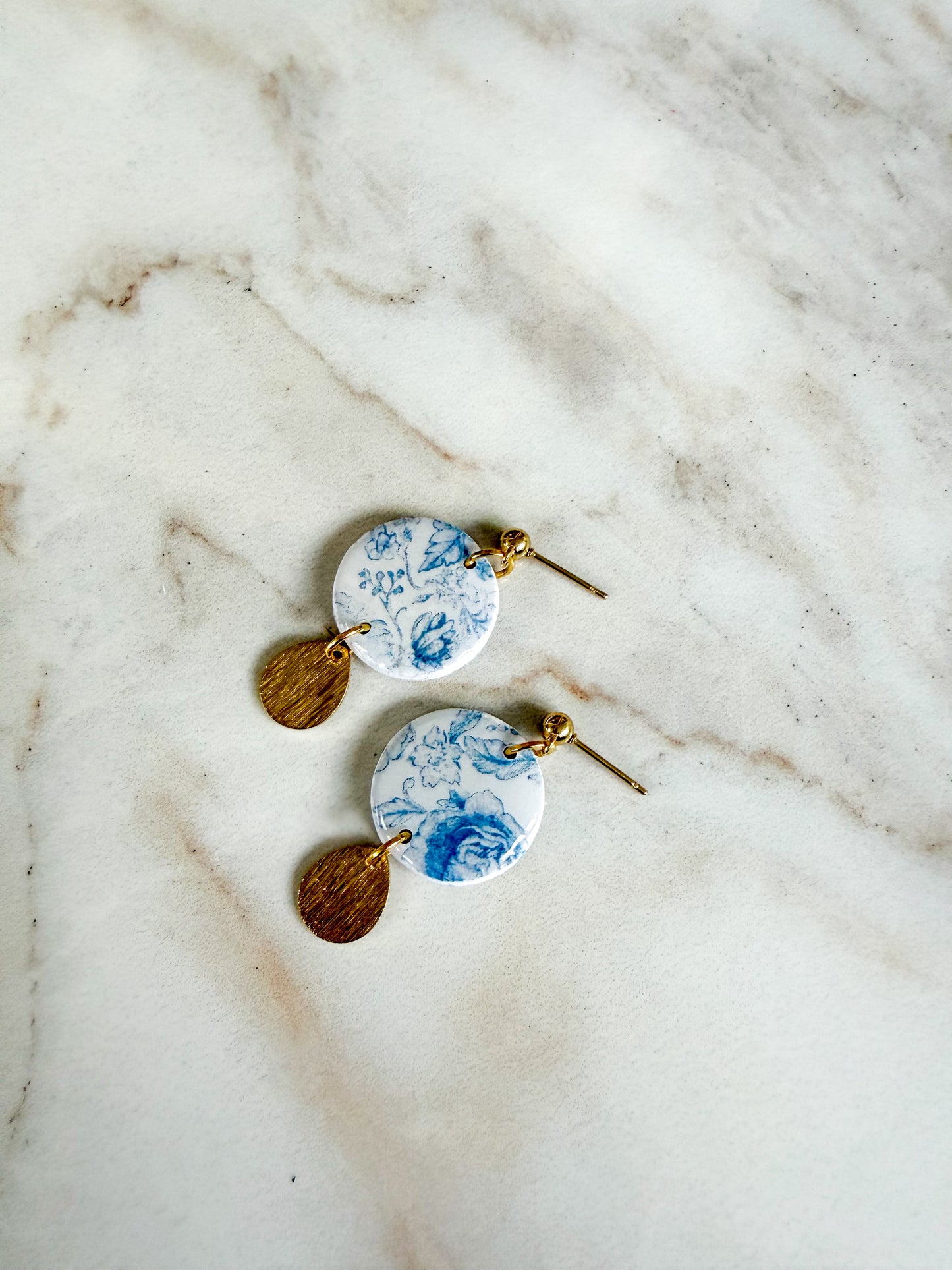 Pair of earrings with floral design on a marble surface