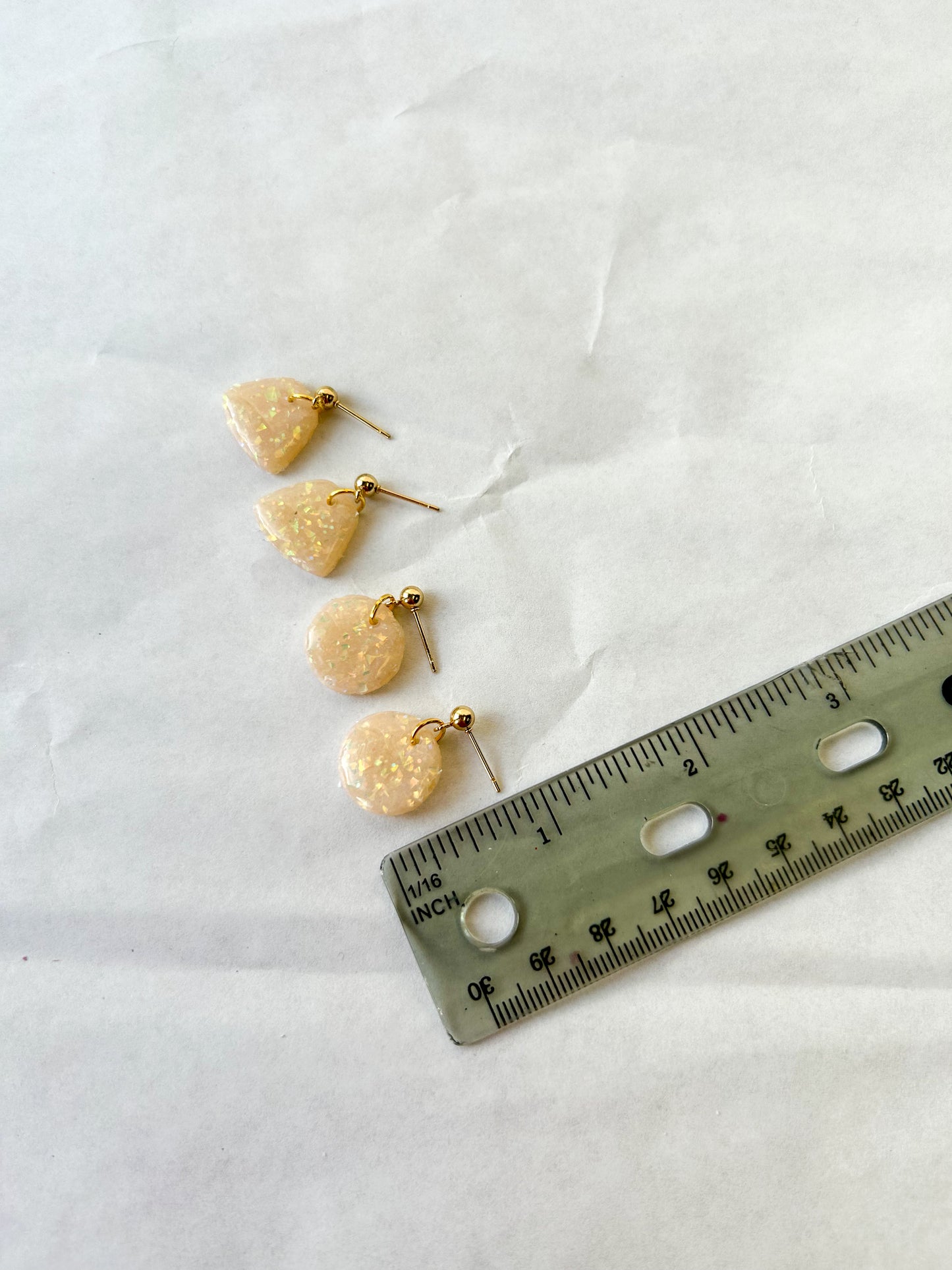 Earrings laying next to a ruler for a scale to show that they are less than 1 inch long