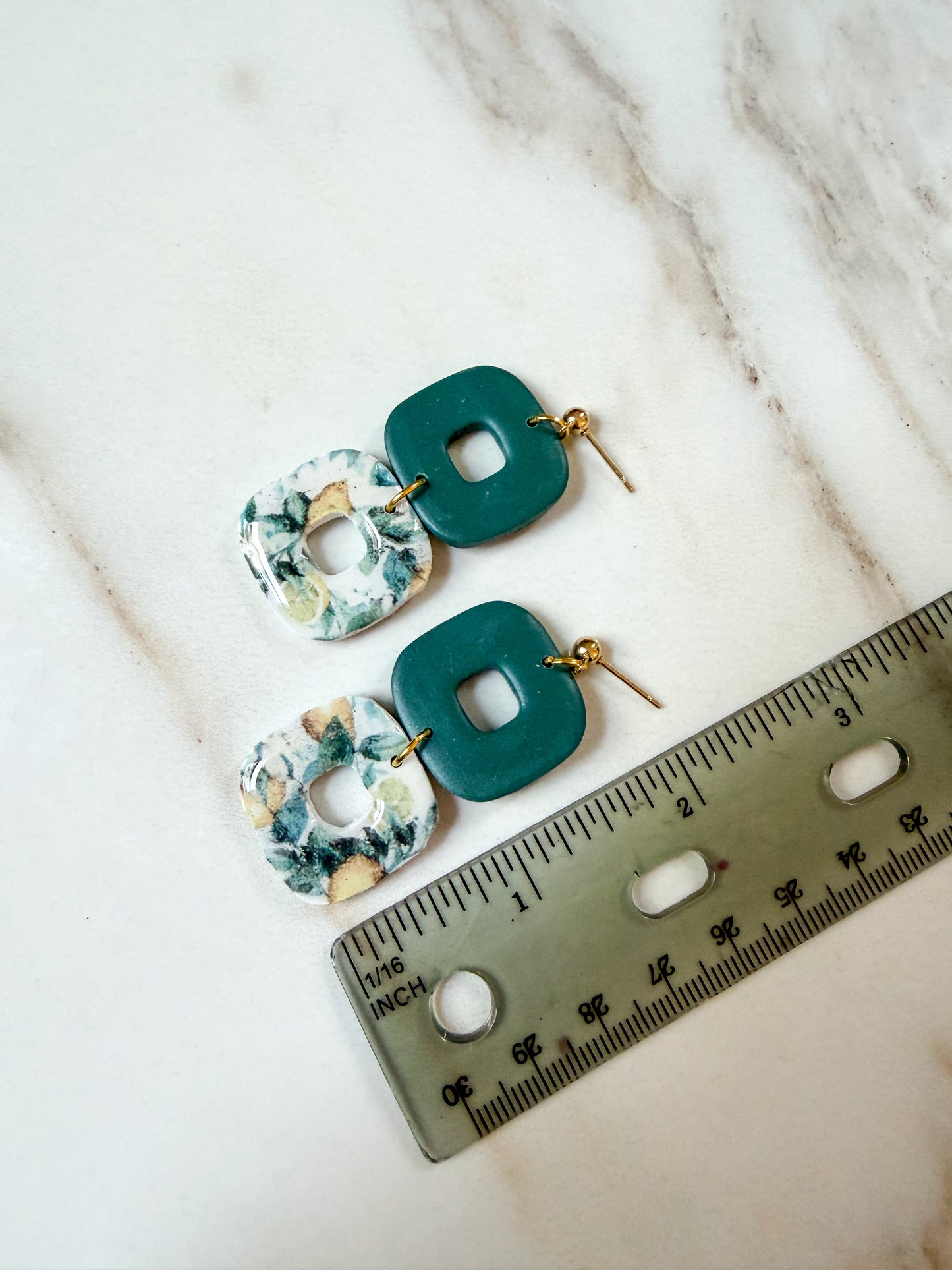 A pair of dangle earrings next to a ruler. About 2 inches in length. 