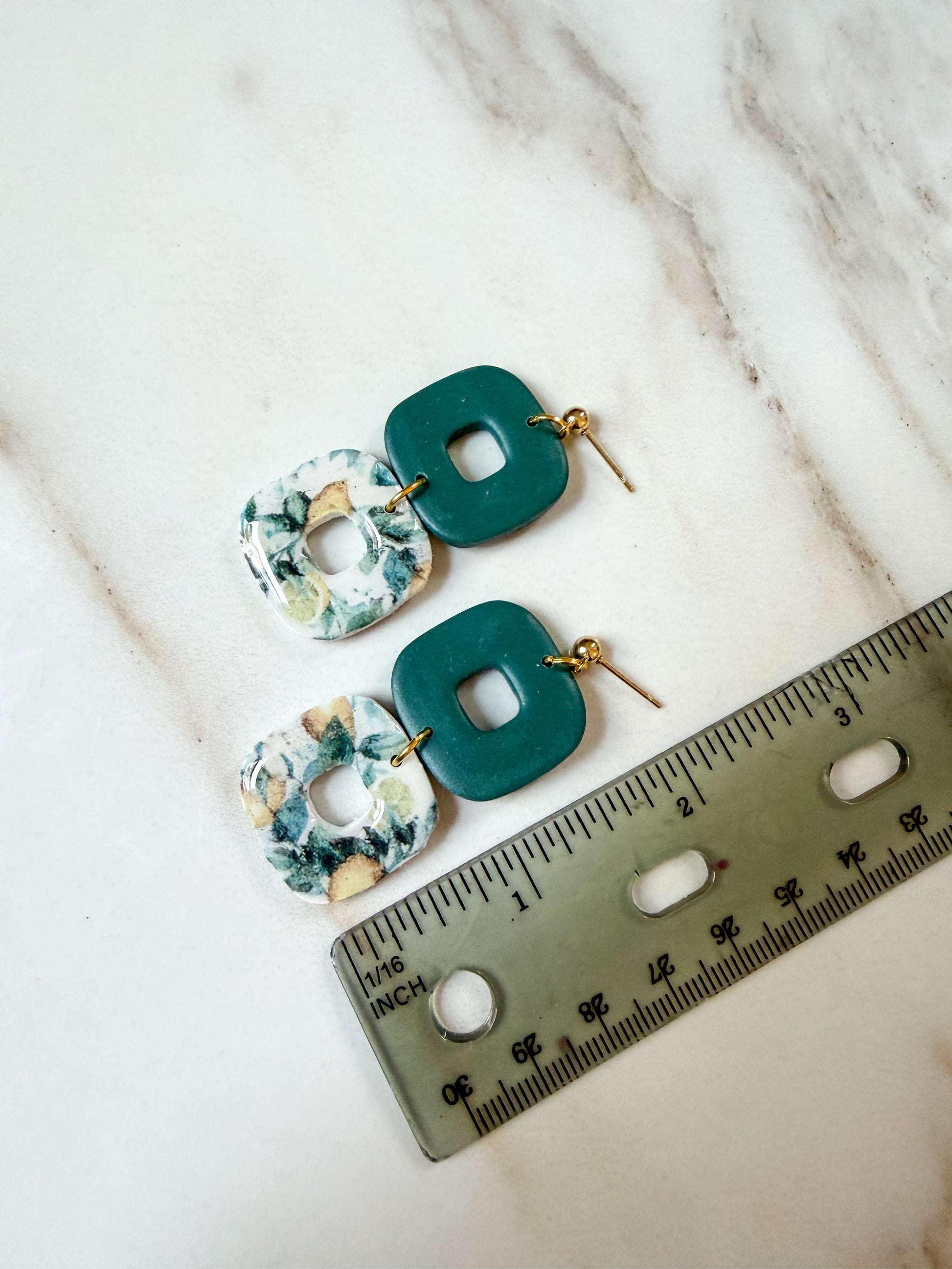 A pair of dangle earrings next to a ruler. About 2 inches in length. 