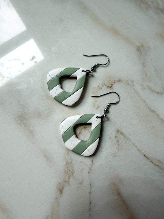 Green and white striped earrings on a marble surface. 