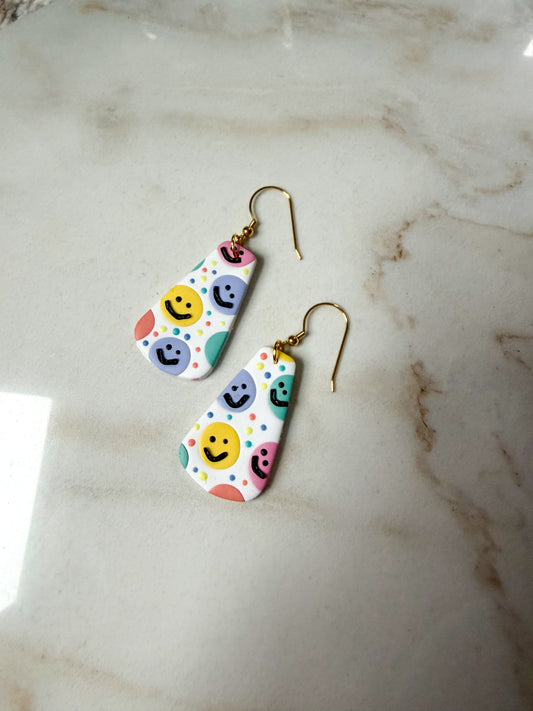 Colorful smiley face earrings on a marble surface