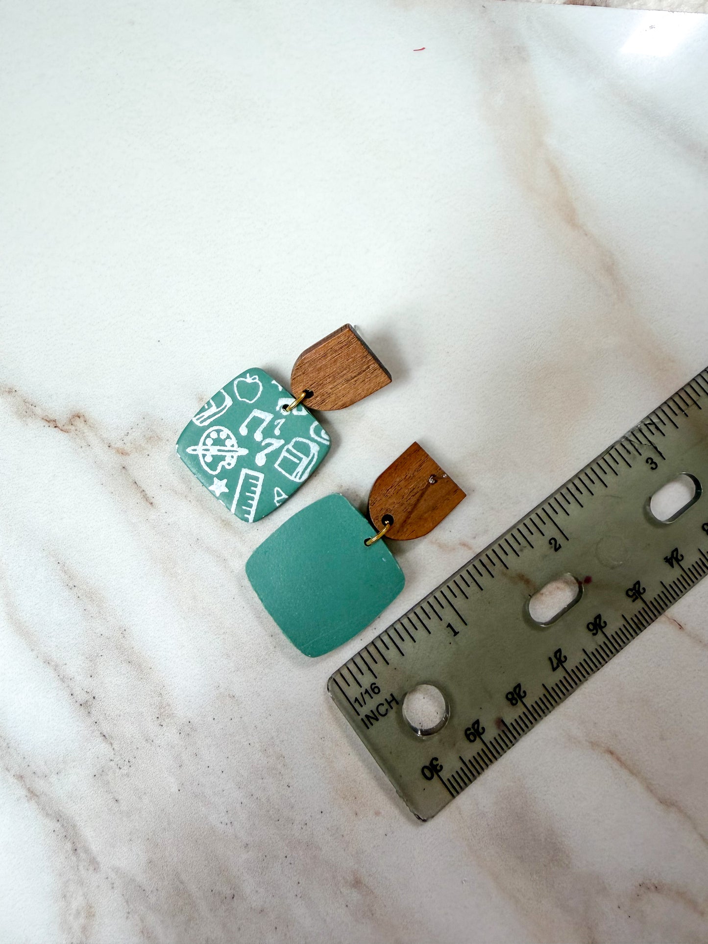 Larger earring next to a ruler for scale. About 1 5/6 inches long. 