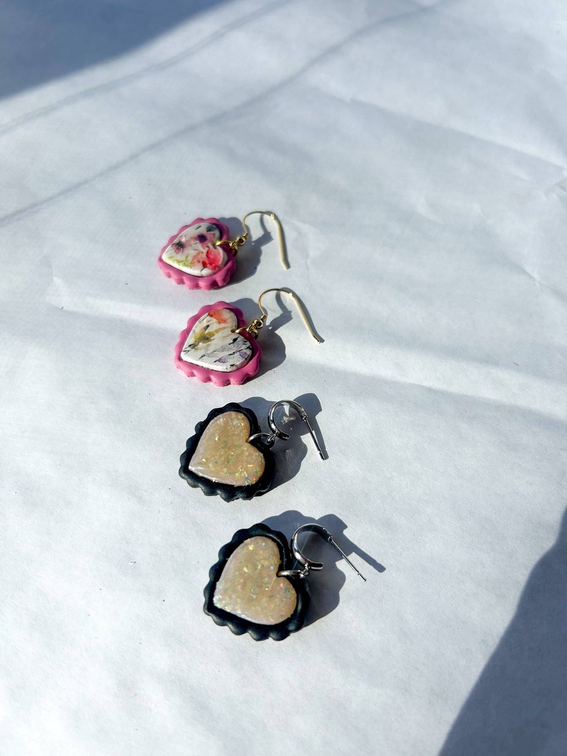 Heart-shaped earrings with pink and gold accents on a white surface