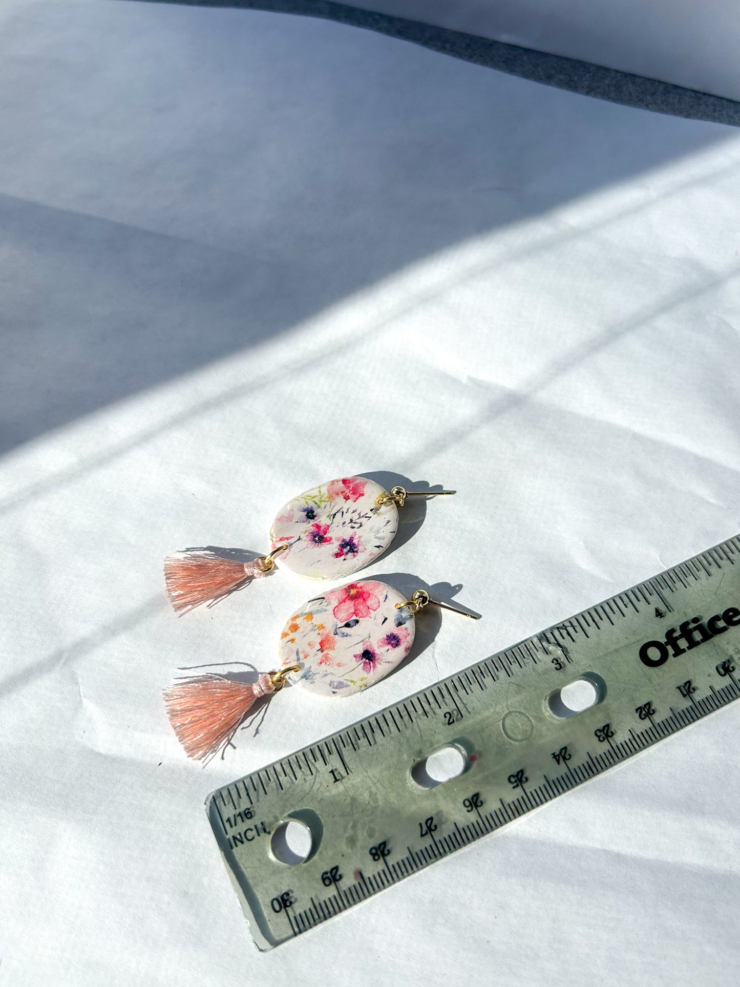 Pair of floral earrings with tassels on a white surface next to a ruler for scale. 2 1/2 inches in length