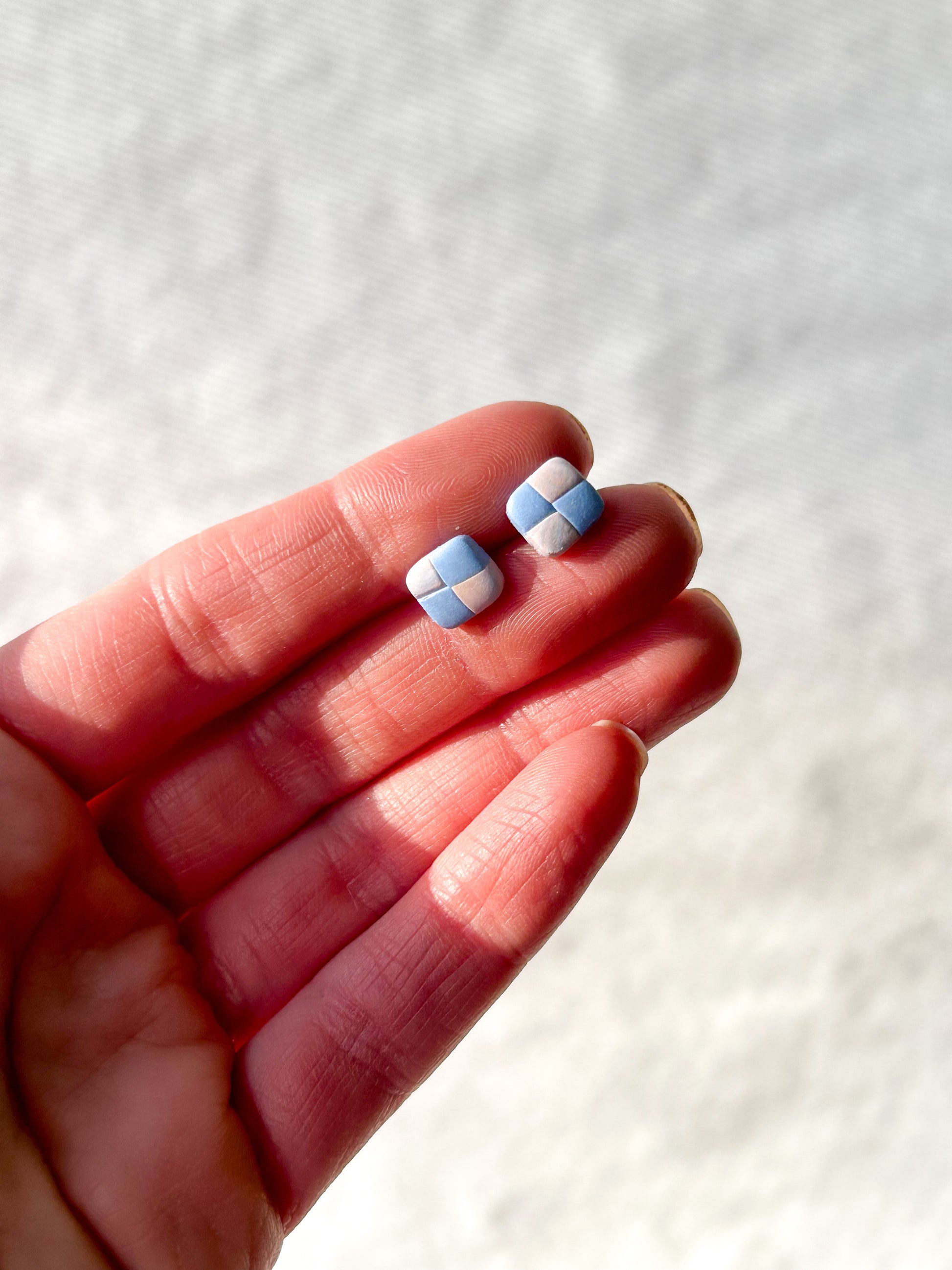 Hand holding a single pair of checker earrings