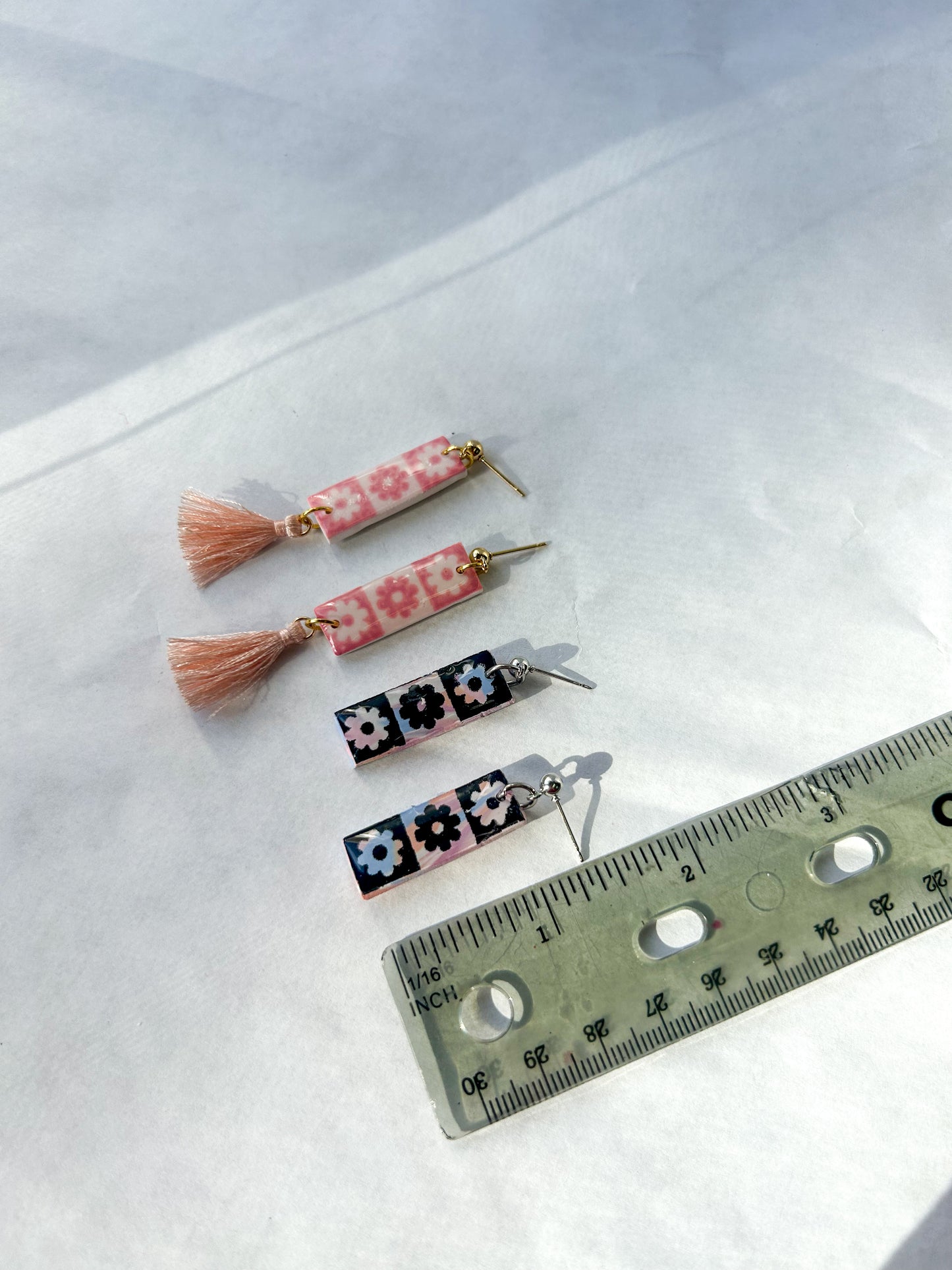 Set of floral tassel earrings on a white surface with a ruler for scale. 1.25 inches long 