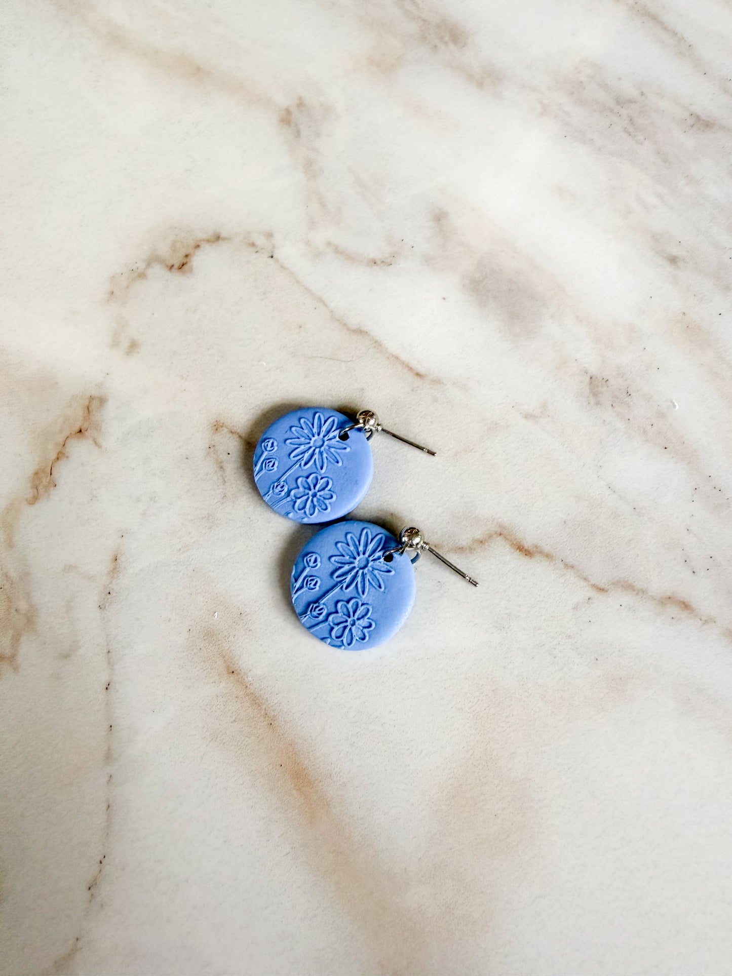 Blue ceramic earrings on a marble surface