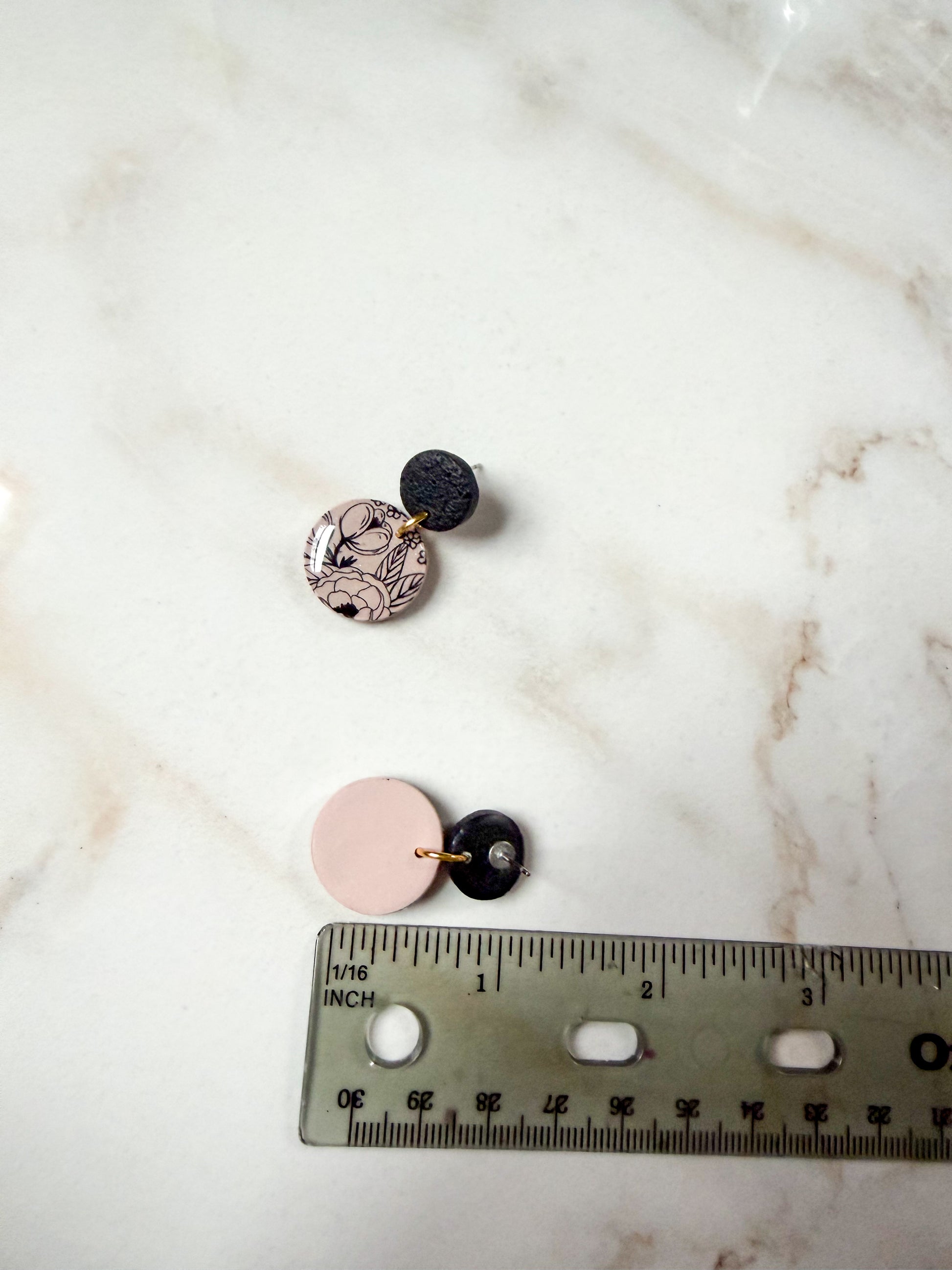 Floral earrings next to a ruler for scale. About one inch in length. 