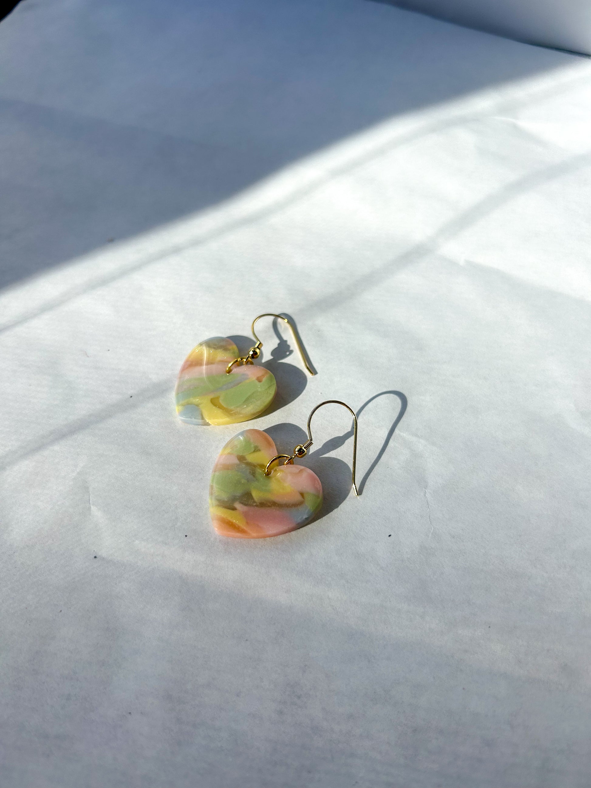 Heart-shaped earrings with a marbled design on a white surface.