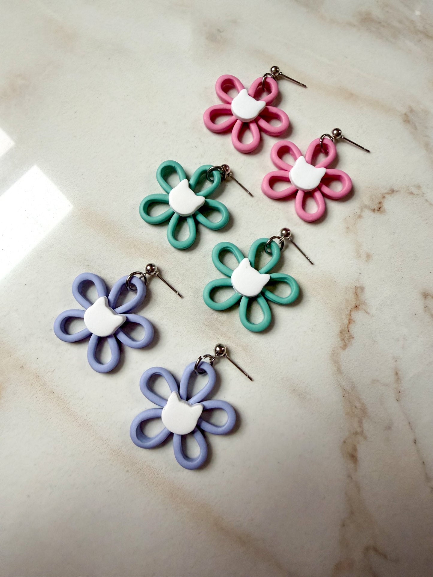Flower dangles with a white cat head in the center. 