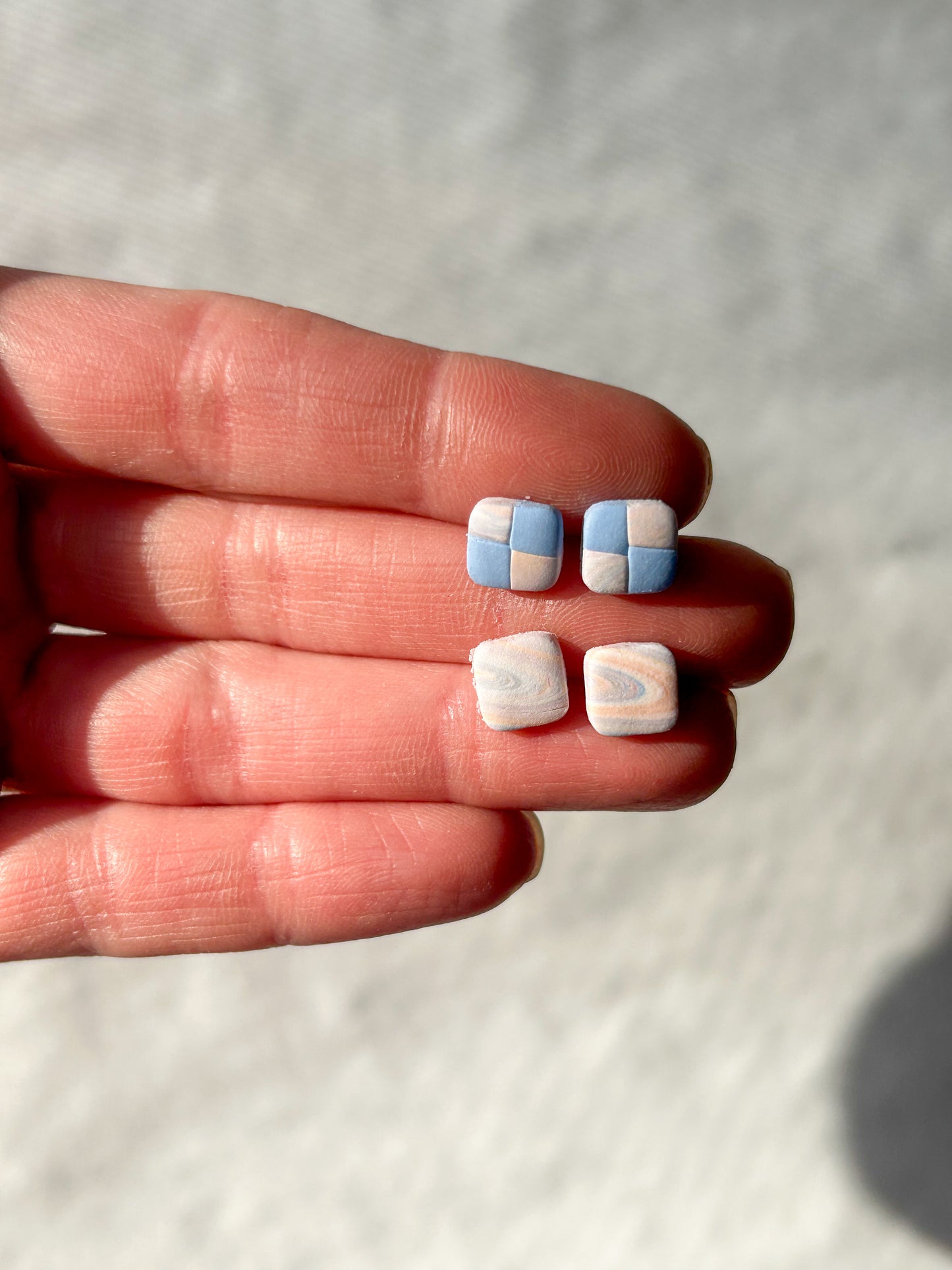 A hand holding two pairs of stud earrings