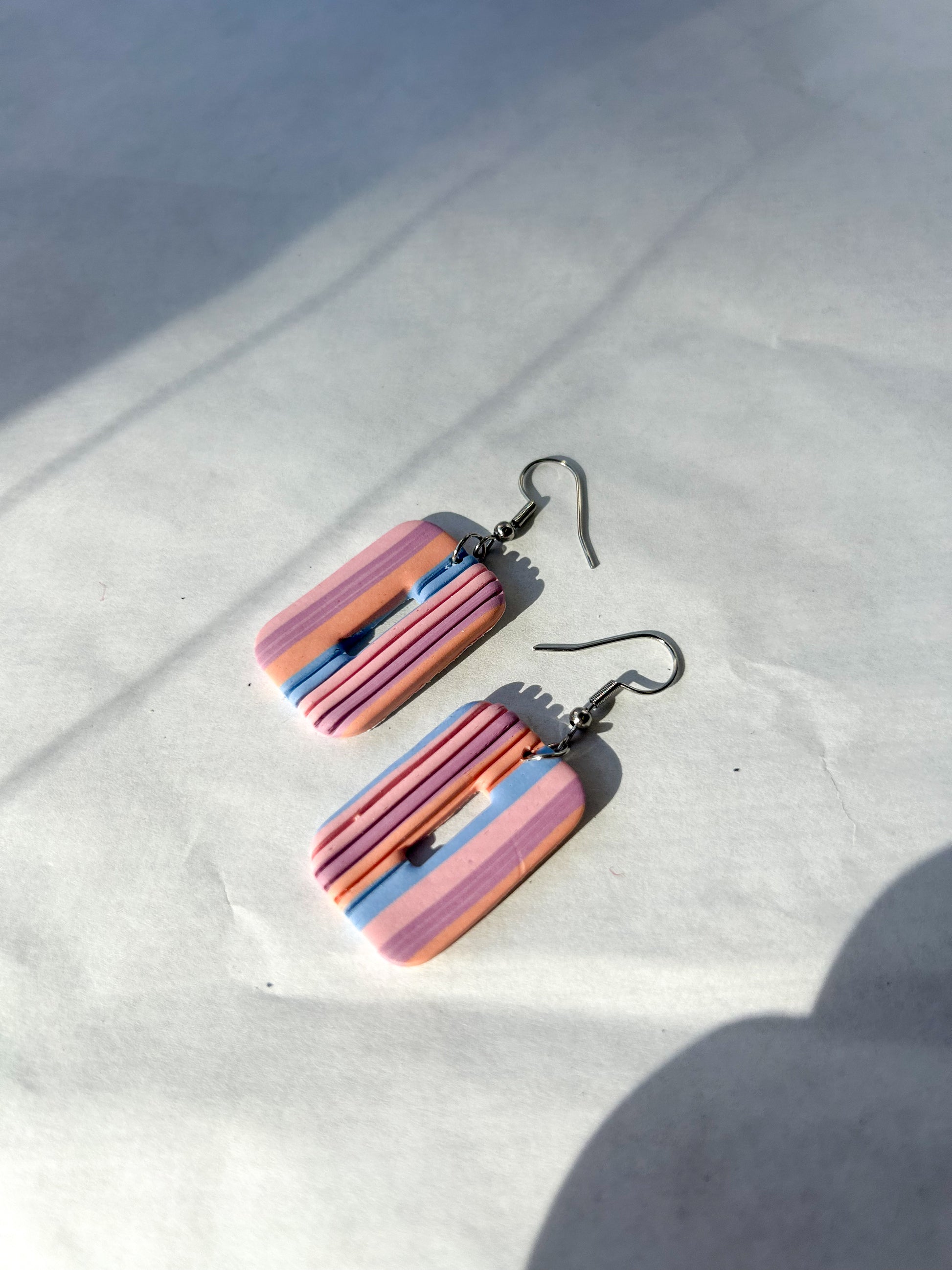 Colorful striped earrings on a white surface with a blurred background
