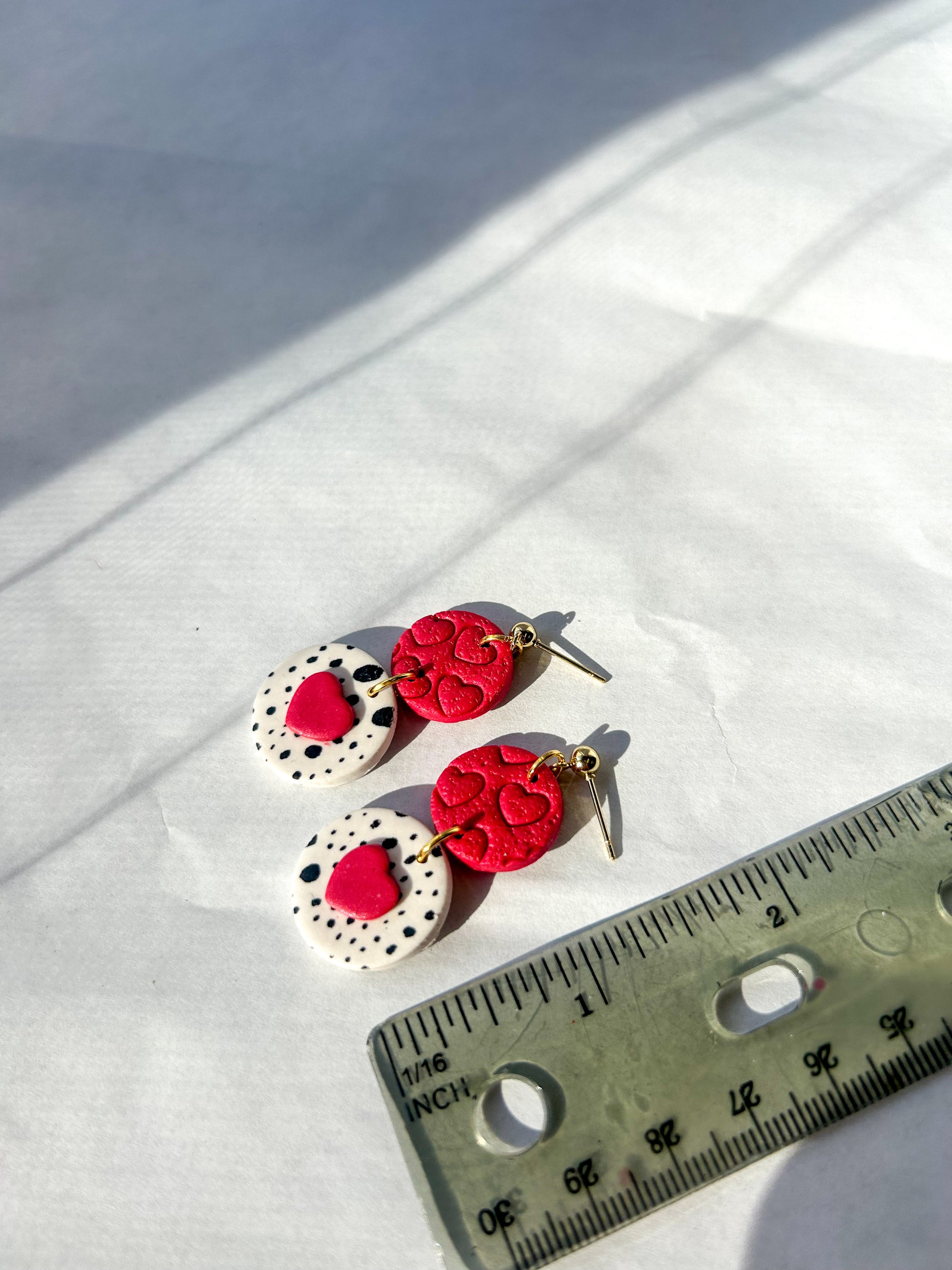 Pair of red and white earrings on a white surface with a ruler for scale. 1.5 inches long 
