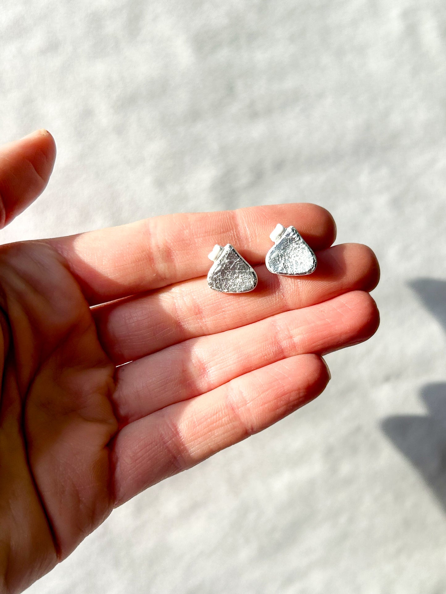 Hand holding two studs that look like chocolate drop candies