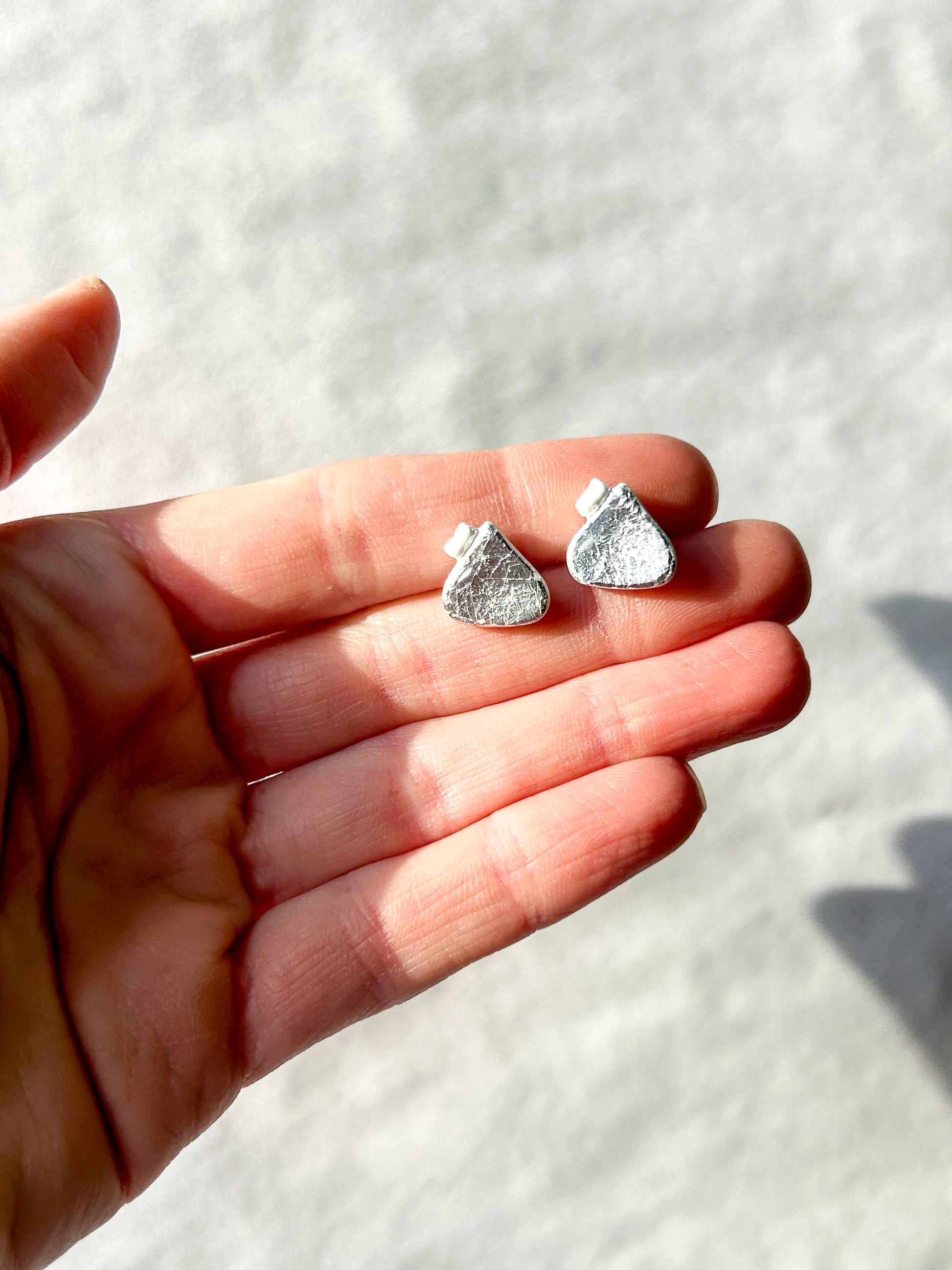 Hand holding two studs that look like chocolate drop candies