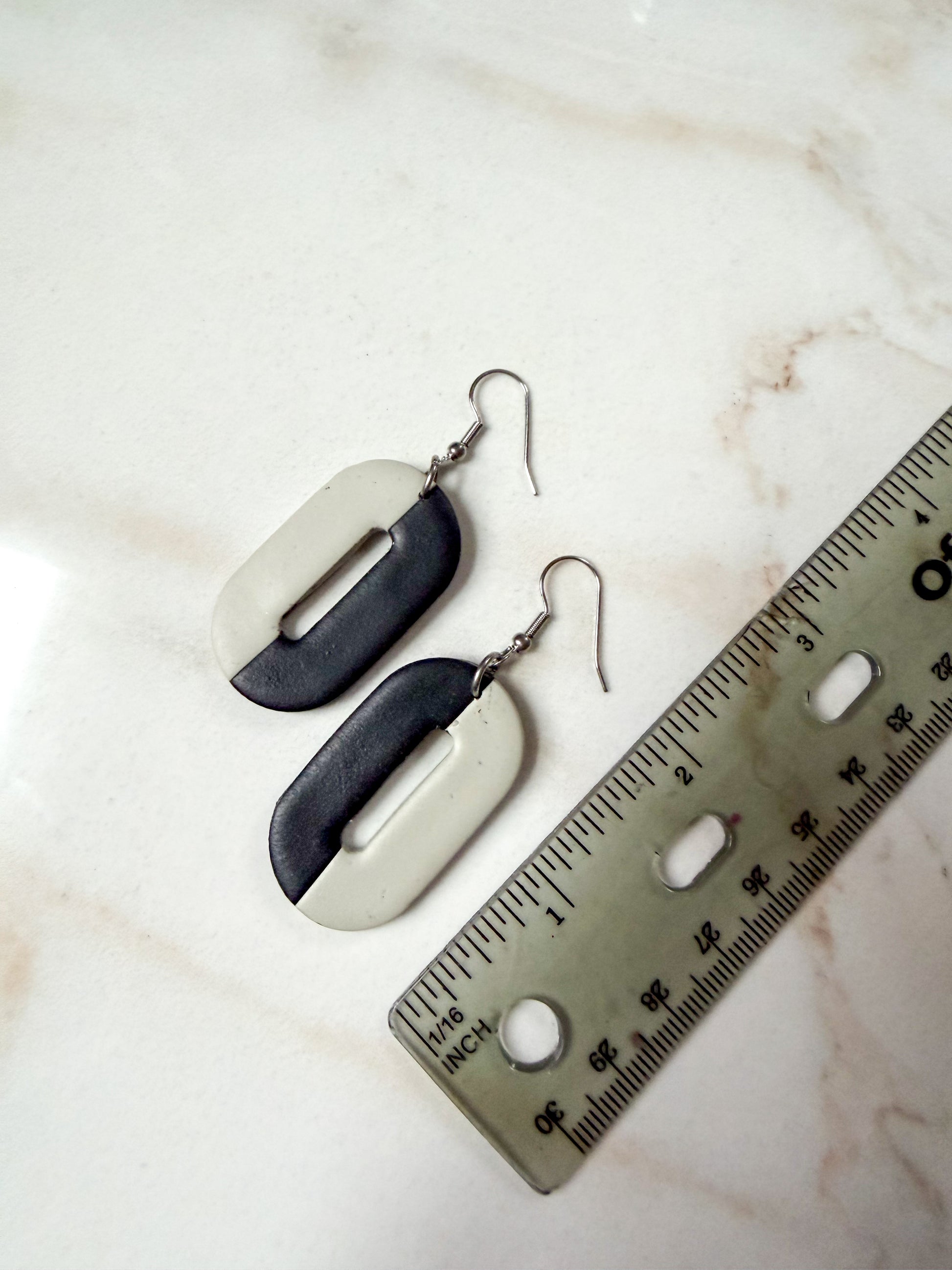 Pair of earrings with a ruler for scale on a marble surface. About 2 1/2 inches long.